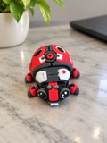 Ladybug-shaped clicker toy with red, black, and white details on a marble surface, branded by DJM 3D SHOP.